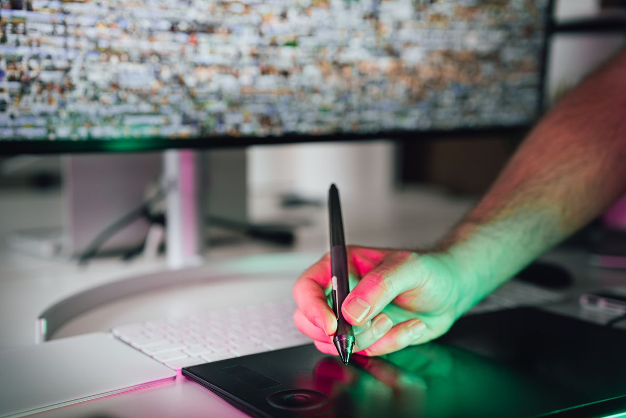 A digital artist using a graphics tablet and stylus in a modern workspace. High-tech creative process.